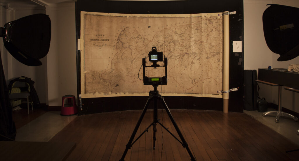 Map Degwm mawr ar wal magnetig, gyda chamera ddigidol wedi'i gosod o'i flaen.